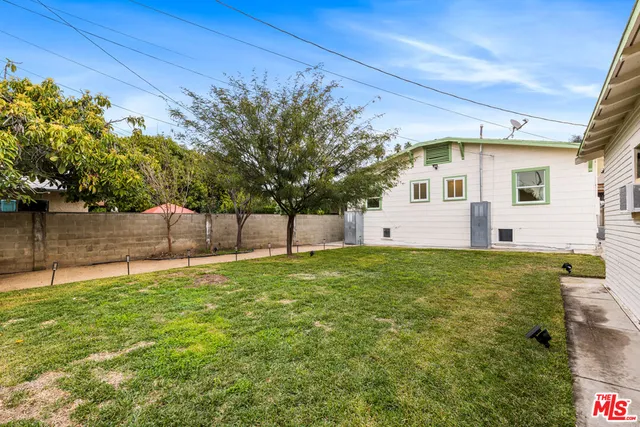 a backyard of a house with plants and large tree