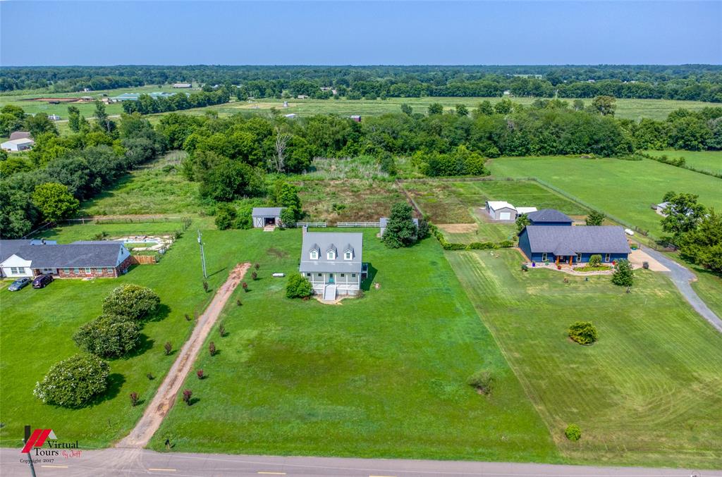 179 Ranchtown Road Elm Grove, LA 71051 - Photo 24 of 26 Expansive property featuring a central Cape Cod-style residence with three dormer windows, a detached shed, a secondary structure with an attached garage, and vast green spaces