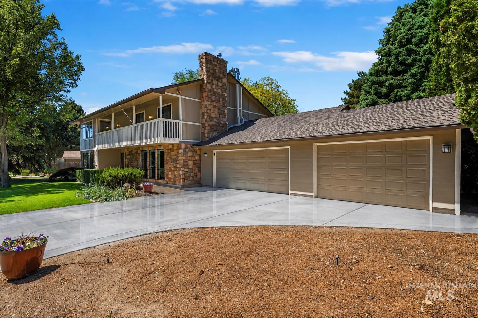 599 Pebble Beach Way Eagle, ID 83616 - Photo 3 of 44 Two-story residence featuring a stone-clad facade, an upper-level balcony with white railings, and a prominent stone chimney