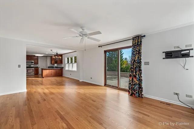 an empty room with wooden floor and a ceiling fan