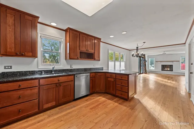 a kitchen with stainless steel appliances granite countertop wooden cabinets a sink and dishwasher with wooden floor