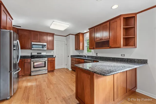 a kitchen with stainless steel appliances granite countertop a stove a sink dishwasher a refrigerator and a oven with wooden floor