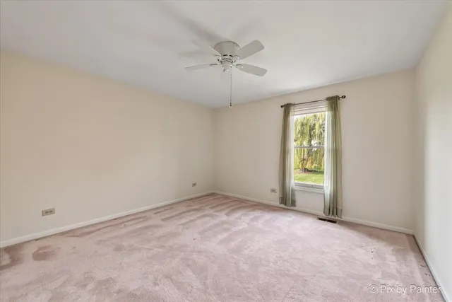 an empty room with a ceiling fan and window