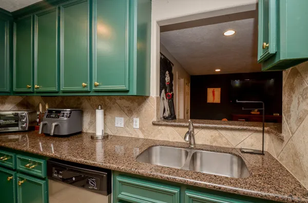 a kitchen with granite countertop a sink a stove and cabinets