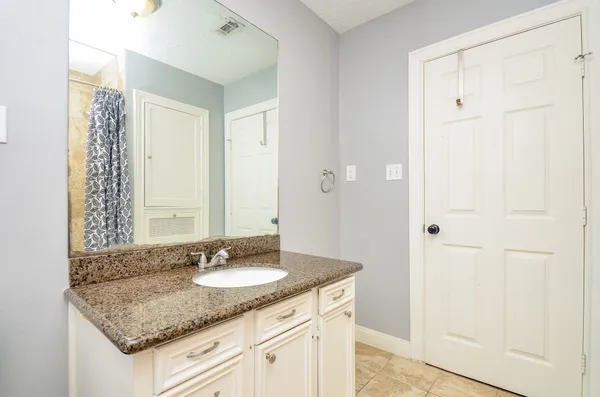 a bathroom with a granite countertop sink and a mirror