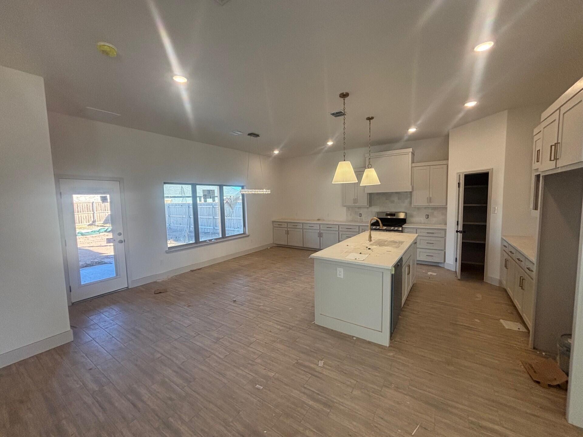 3616 119th Street Lubbock, TX 79423 - Photo 2 of 9 a large white kitchen with a refrigerator a stove a sink dishwasher and wooden cabinets with wooden floor