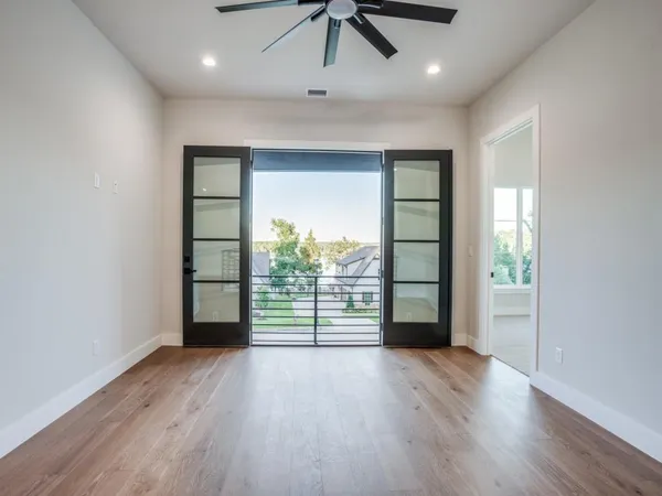 an empty room with a ceiling fan and wooden floor
