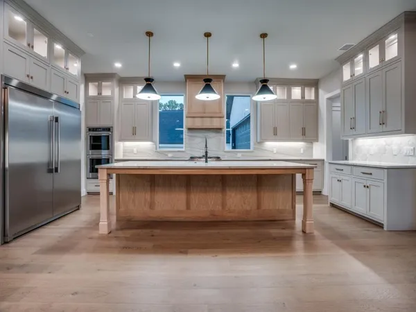 a kitchen with kitchen island granite countertop a sink cabinets and stainless steel appliances