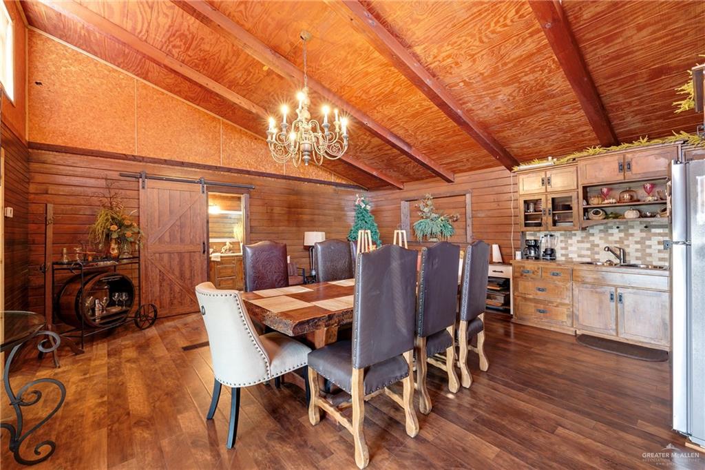 32447 Farm To Market Road 2925 Rio Hondo, TX 78583 - Photo 5 of 25 Dining room with a barn door, lofted ceiling with beams, dark wood-style flooring, wood walls, and a notable chandelier