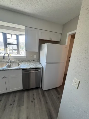 a kitchen with granite countertop white cabinets and white appliances