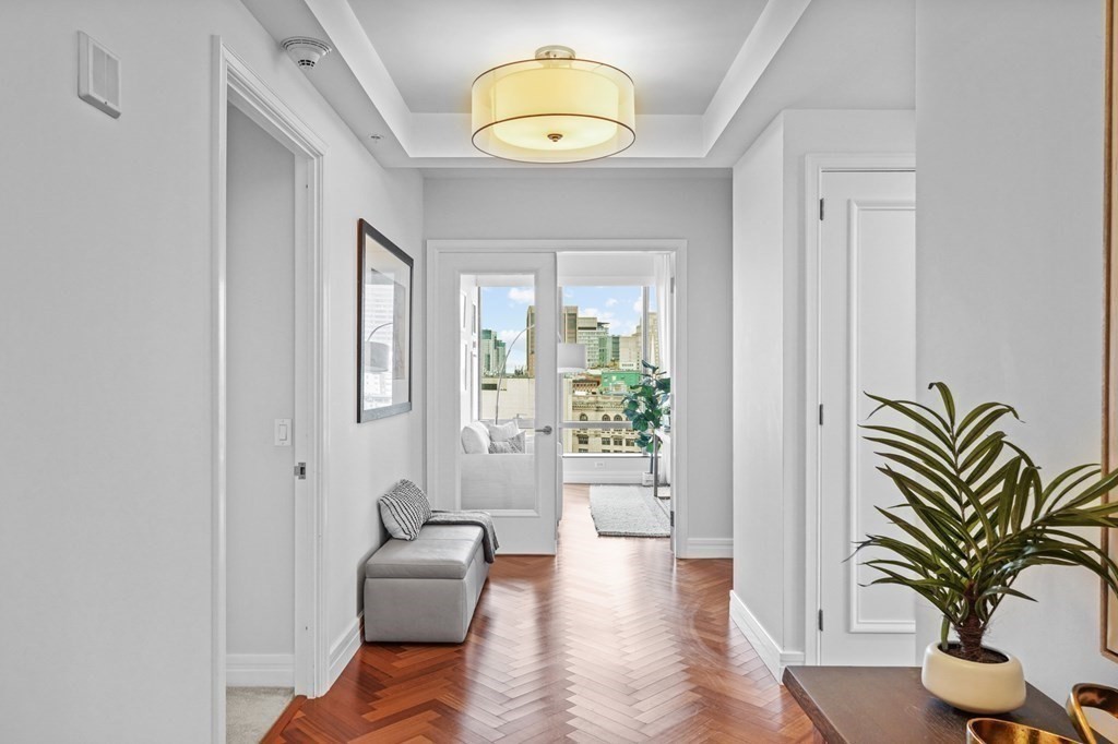 1 Avery Street, Unit U19D Boston, MA 02111 - Photo 13 of 27 a hallway with a couch and chandelier