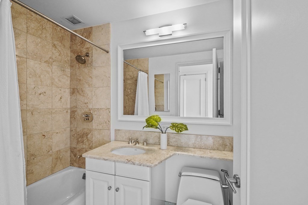 1 Avery Street, Unit U19D Boston, MA 02111 - Photo 20 of 27 a bathroom with a granite countertop sink a mirror a shower and a bathtub