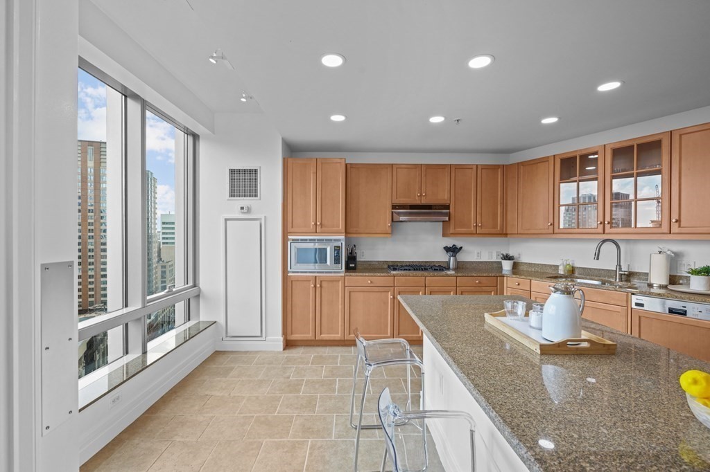 1 Avery Street, Unit U19D Boston, MA 02111 - Photo 8 of 27 a large kitchen with stainless steel appliances granite countertop a stove a sink and a refrigerator