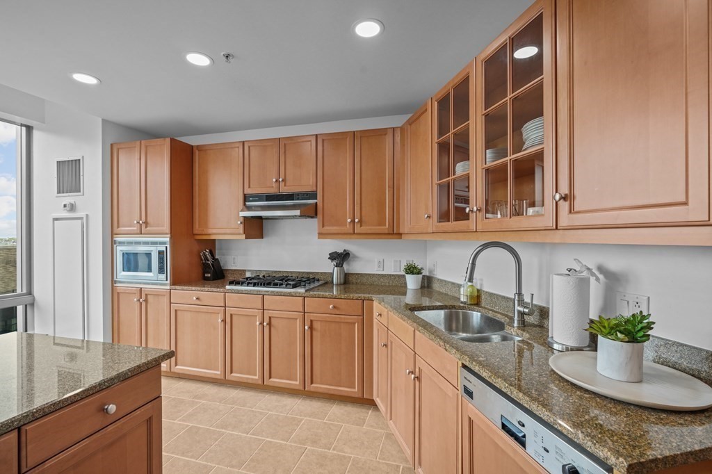 1 Avery Street, Unit U19D Boston, MA 02111 - Photo 10 of 27 a kitchen with kitchen island granite countertop a sink stainless steel appliances and cabinets