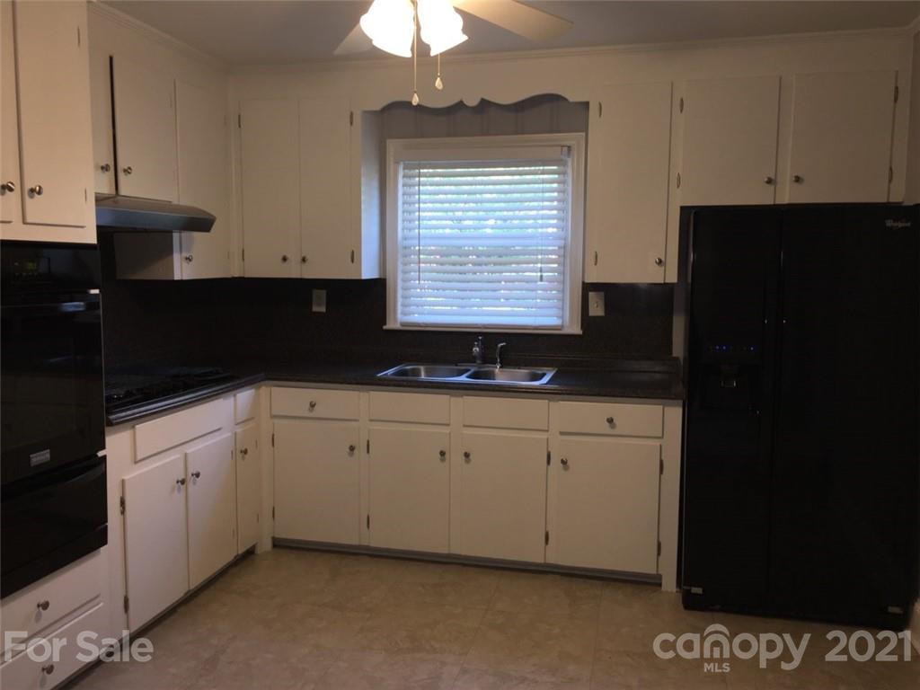 3633 Kempton Place Charlotte, NC 28208 - Photo 28 of 32 a kitchen with granite countertop white cabinets and black appliances
