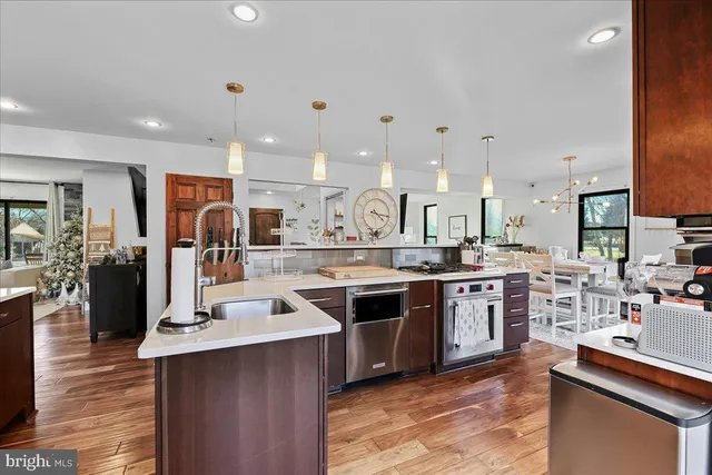 a dining hall with stainless steel appliances granite countertop a stove and a wooden floors