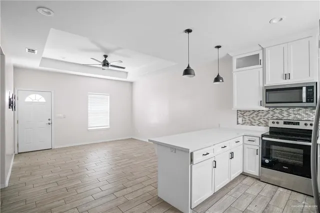 a kitchen with stainless steel appliances white cabinets and wooden floor