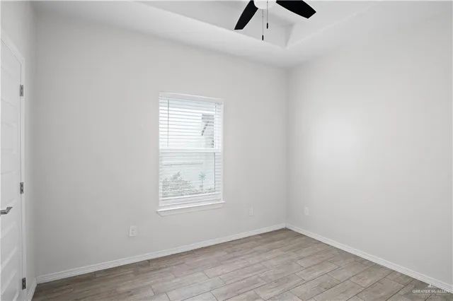 an empty room with ceiling fan and windows