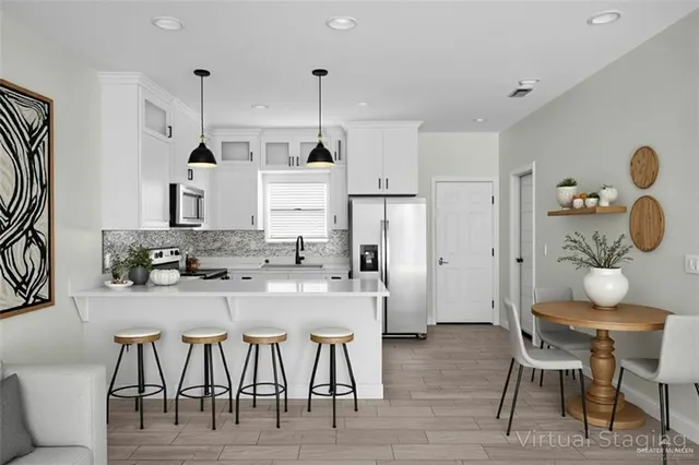 a kitchen with stainless steel appliances granite countertop a table chairs stove and refrigerator