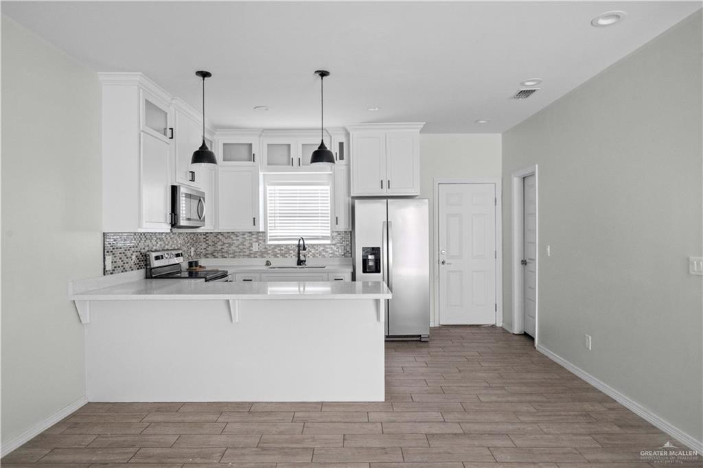 1511 Playa Drive, Unit 2 Weslaco, TX 78596 - Photo 7 of 28 a kitchen with kitchen island stainless steel appliances a sink and a refrigerator