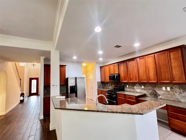 a kitchen with stainless steel appliances granite countertop sink stove refrigerator and cabinets