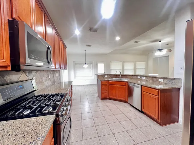 a kitchen with stainless steel appliances granite countertop a stove a sink and a microwave