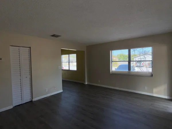 an empty room with wooden floor and windows