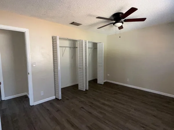 an empty room with wooden floor closet and windows