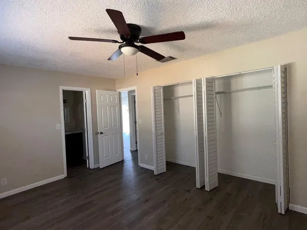 a view of empty room with wooden floor and ceiling fan