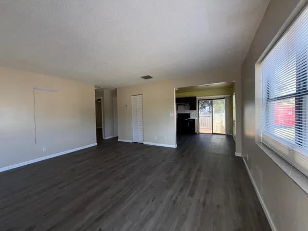 an empty room with wooden floor and windows