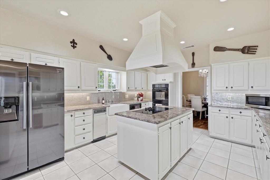 6955 Hawk Road Flower Mound, TX 75022 - Photo 15 of 40 Bright kitchen featuring white cabinetry, granite countertops, stainless steel appliances, a center island with a cooktop, and tile flooring