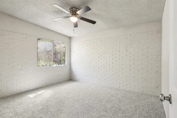 an empty room with a ceiling fan and a window