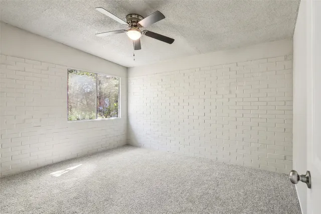 an empty room with a ceiling fan and a window