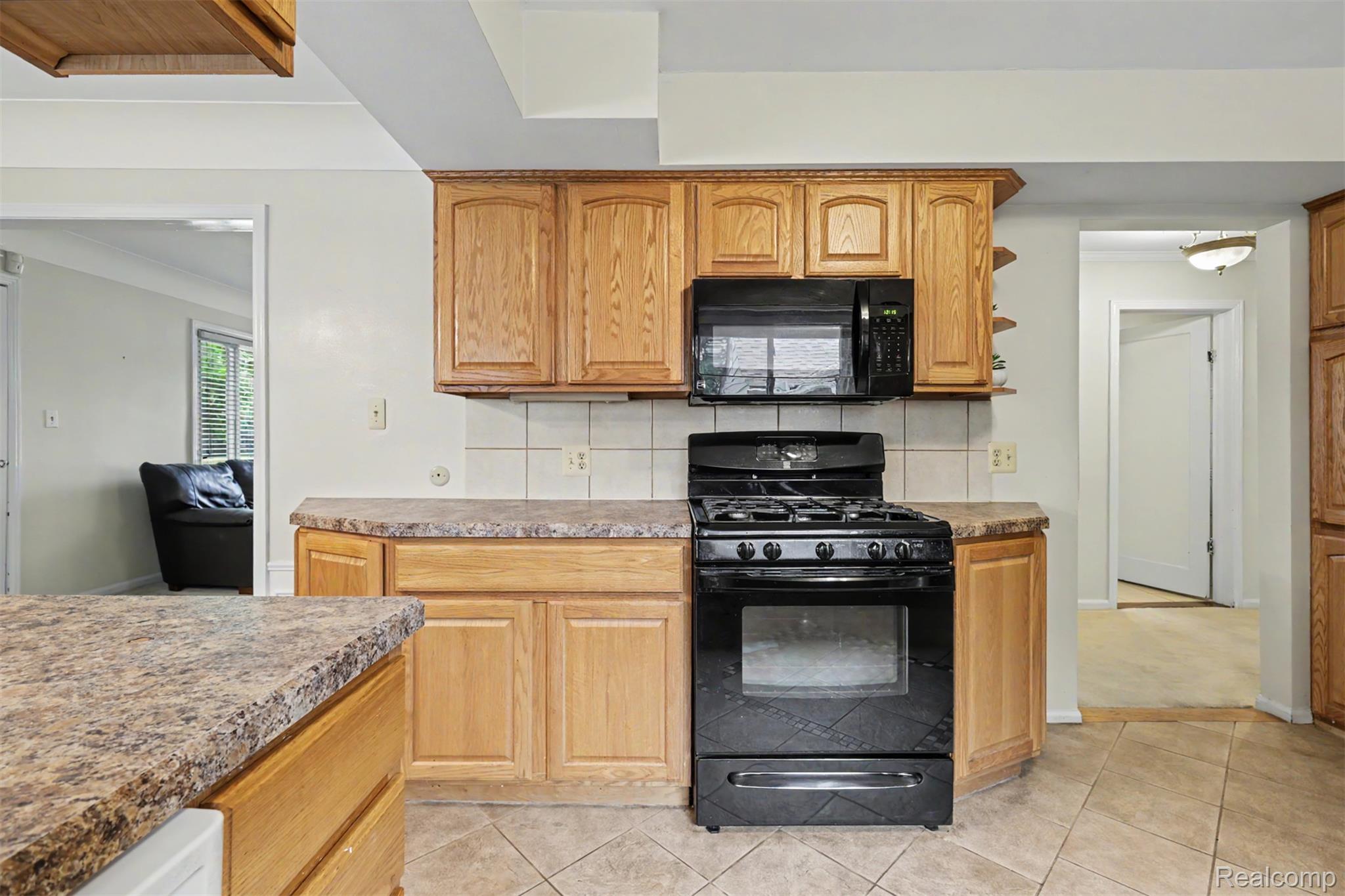 7136 Rosedale Boulevard Allen Park, MI 48101 - Photo 19 of 51 Kitchen featuring light wood cabinetry, tiled backsplash, black range, black microwave, and tiled flooring
