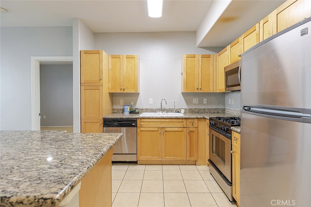 100 South Alameda Street, Unit 353 Los Angeles, CA 90012 - Photo 16 of 60 a kitchen with stainless steel appliances granite countertop a sink stove and refrigerator