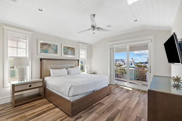 a bedroom with a large bed a flat tv screen and dresser