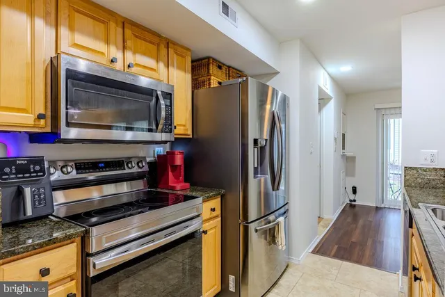 a kitchen with stainless steel appliances granite countertop a refrigerator and a stove top oven