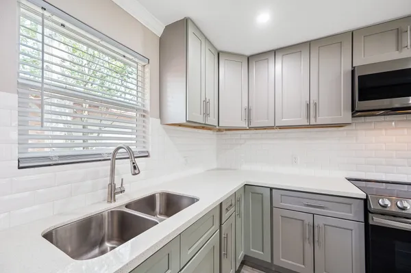 a kitchen with stainless steel appliances white cabinets sink and window