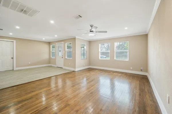 a view of an empty room with wooden floor and a window