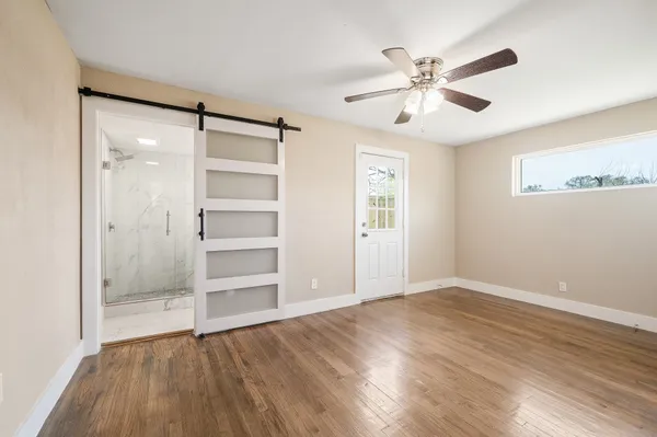 a view of an empty room with a window and wooden floor