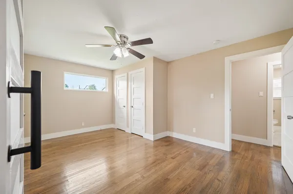a view of empty room with wooden floor and fan