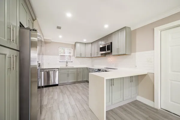 a kitchen with a sink a counter top space stainless steel appliances and cabinets