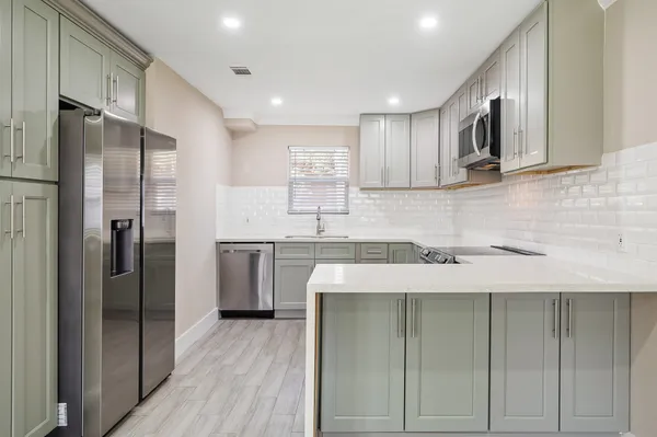 a kitchen with stainless steel appliances granite countertop a refrigerator a sink and a stove