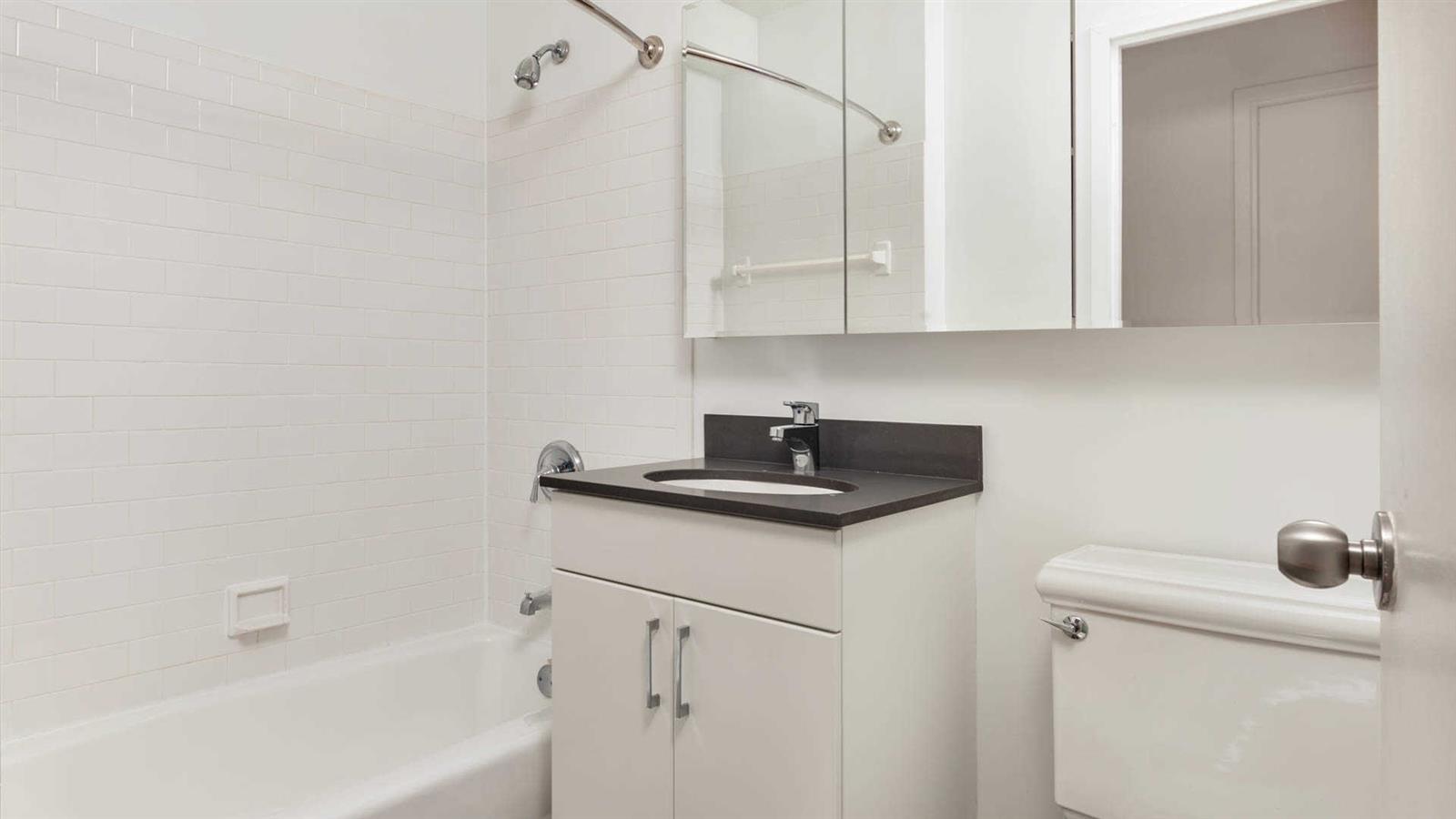 a bathroom with a granite countertop sink a toilet and bathtub