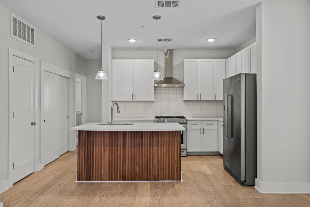 2827 Manor Road, Unit 2201 Austin, TX 78722 - Photo 11 of 40 Open-concept kitchen featuring a wood-finish island with a white countertop and undermount sink