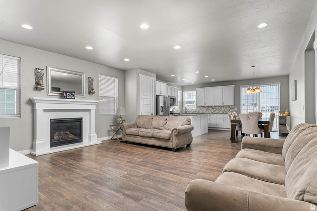 5686 Duke Lane Tooele, UT 84074 - Photo 28 of 38 Living room featuring dark wood finished floors, a chandelier, and a glass covered fireplace