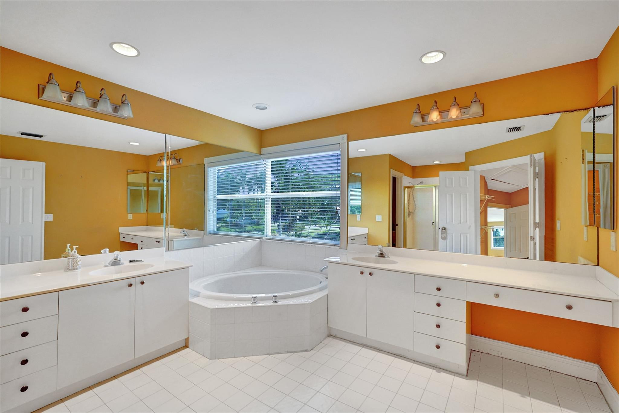 10902 Tamoron Lane Boca Raton, FL 33498 - Photo 36 of 66 a spacious bathroom with a double vanity sink a large mirror and a bathtub