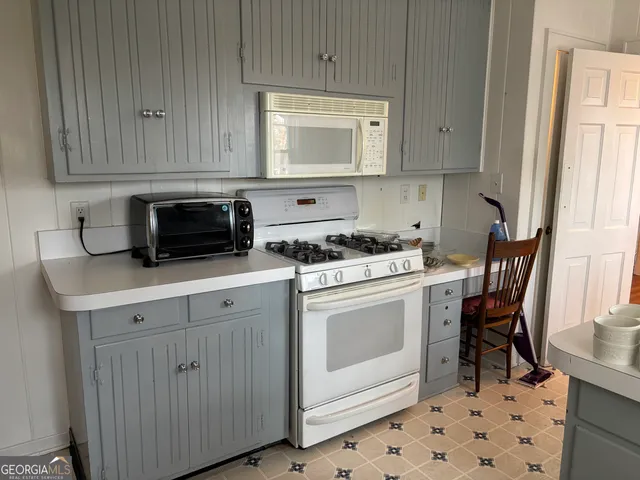 a kitchen with white cabinets and white appliances