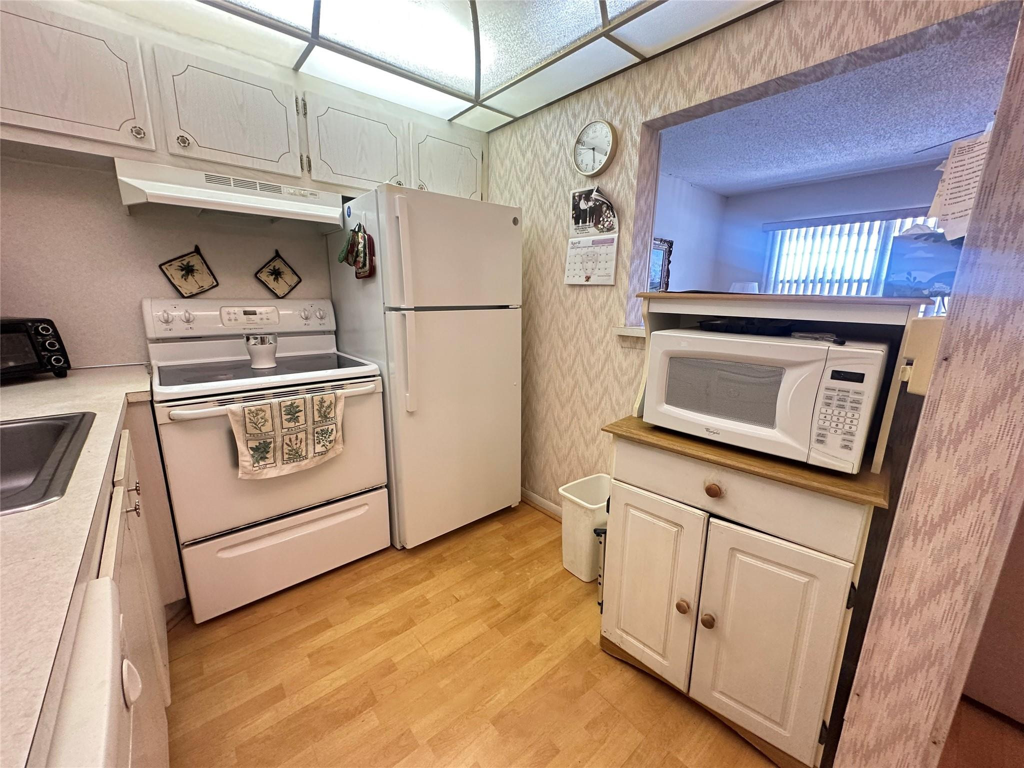 263 Farnham K, Unit 263 Deerfield Beach, FL 33442 - Photo 11 of 48 a kitchen with white cabinets and white appliances
