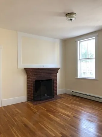 a view of empty room with wooden floor and fireplace